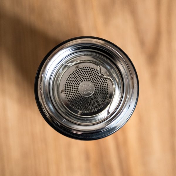 butilka-s-filtar-termo Top view of stainless steel tea infuser inside a black thermos.