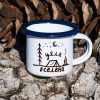 White enamel mug with blue rim and camping illustration with the text “My Universe”, placed outdoors on bark.