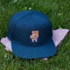 Front view of dark green flat brim cap made from 100% recycled micro twill with embroidered hiking bear