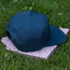 Back view of dark green flat brim cap made from 100% recycled micro twill with adjustable snapback closure
