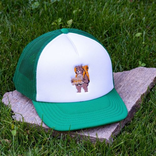 Front view of white and green kids mesh cap made from durable material with embroidered hiking bear carrying a backpack.