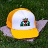 Front view of yellow and white kids mesh cap with embroidered fox wearing sunglasses in front of green mountains, breathable mesh sides and adjustable closure.