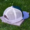 Back view of green and white trucker cap with breathable soft mesh back, adjustable snapback closure and curved light gray visor