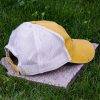 Back view of yellow trucker cap made from organic and recycled cotton with soft mesh back and adjustable closure