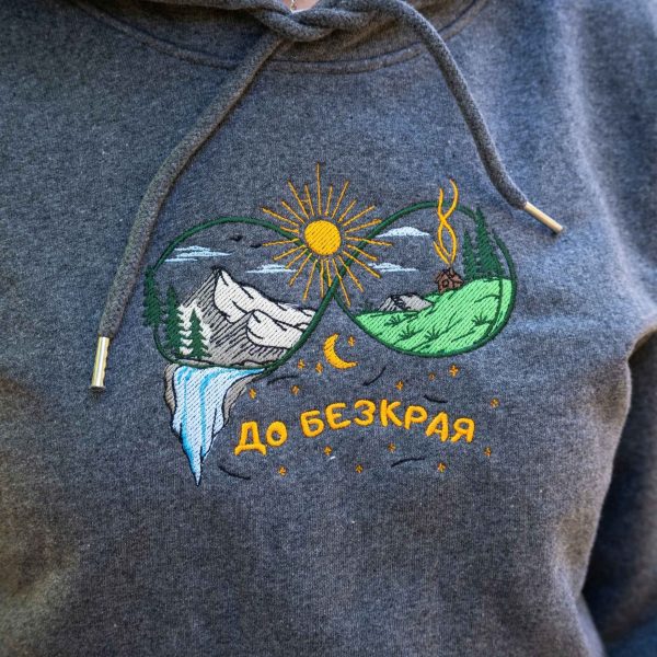 broderia-do-bezkraya-varhu-tumnosiv-suitshart-s-kachulka Close-up of colourful embroidered mountain landscape with “До безкрая” text on a dark grey hoodie