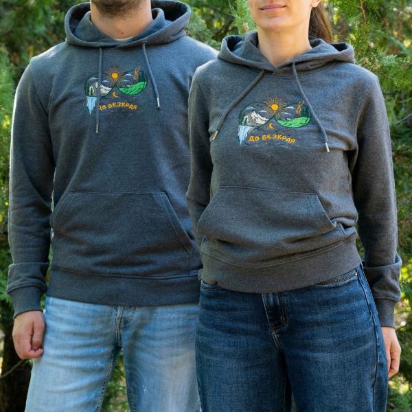 tumnosiv-uniseks-suitshart-s-kachulka-i-broderia-do-bezkraya Man and woman wearing dark grey unisex hoodies with embroidered mountain landscape and “До безкрая” design outdoors