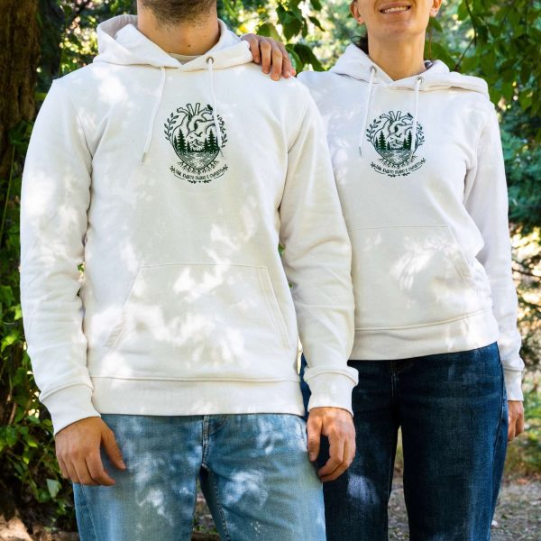 byal-uniseks-suitshart-s-kachulka-i-broderia-sartse Two people wearing white unisex hoodies with embroidered anatomical heart and mountain landscape design outdoors